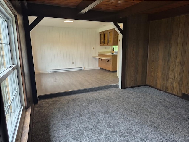 unfurnished living room featuring baseboard heating, wooden walls, beamed ceiling, carpet, and wooden ceiling