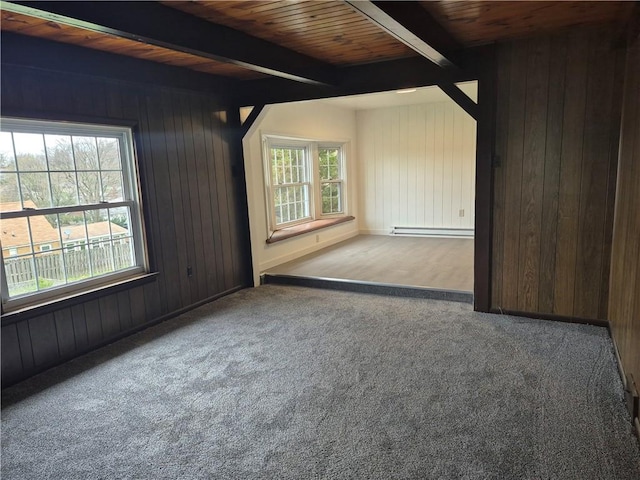 carpeted spare room featuring wooden walls, a baseboard heating unit, and beamed ceiling