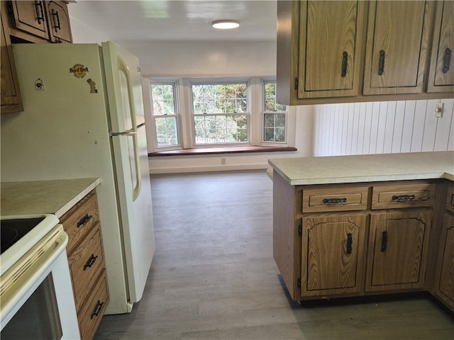kitchen with brown cabinets, light countertops, white range with electric cooktop, and wood finished floors