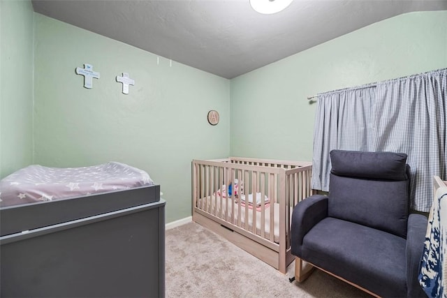 carpeted bedroom with baseboards and a crib