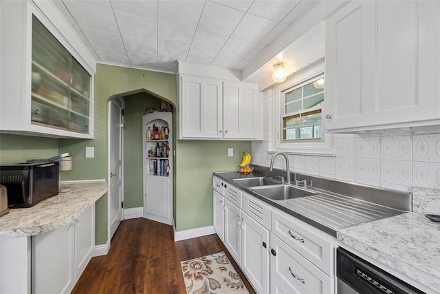 kitchen featuring tasteful backsplash, dark wood-style floors, white cabinets, stainless steel dishwasher, and a sink
