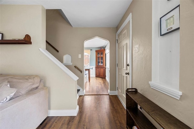 entryway featuring baseboards, stairway, arched walkways, and wood finished floors