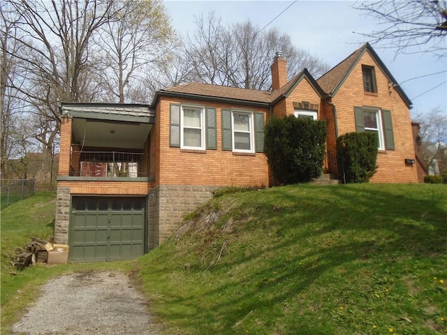 view of front of home with a front yard, an attached garage, a chimney, brick siding, and driveway