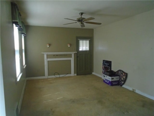 unfurnished living room featuring carpet, baseboards, and a ceiling fan