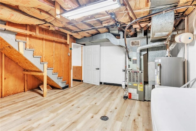 unfinished basement with visible vents, stairway, water heater, wood finished floors, and heating unit