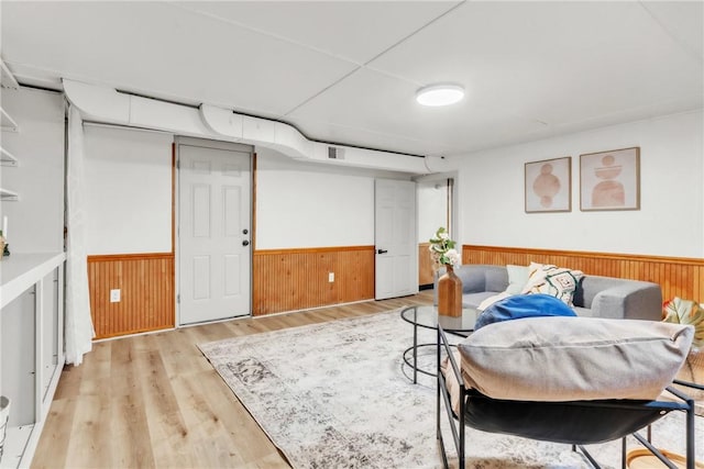 interior space with wooden walls, visible vents, a wainscoted wall, and light wood-style flooring