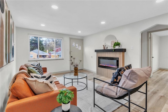 living room featuring a glass covered fireplace, recessed lighting, and light wood-style flooring