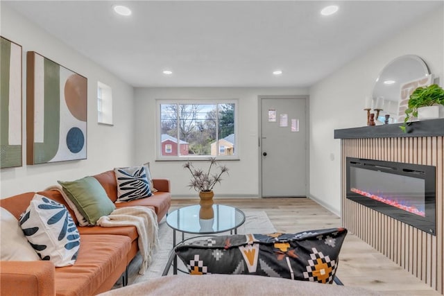 living room with recessed lighting, wood finished floors, and a glass covered fireplace