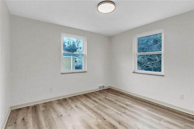 spare room featuring light wood-style floors, baseboards, and visible vents