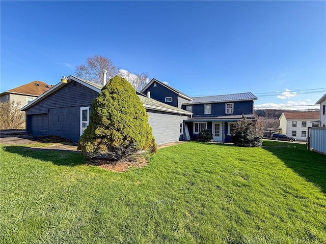 rear view of house featuring a yard, metal roof, and an attached garage