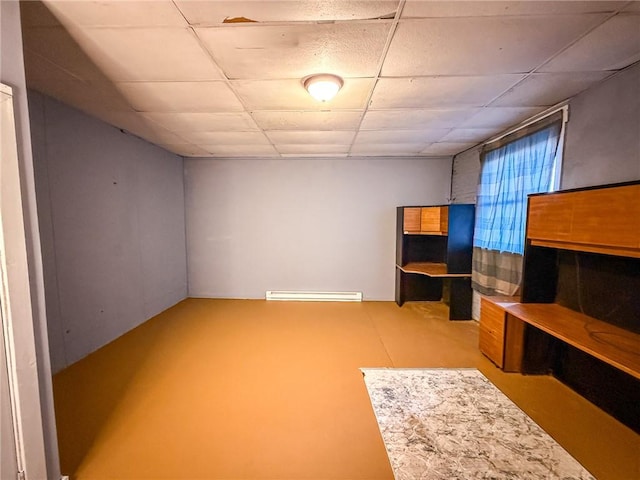 basement featuring a baseboard radiator and a drop ceiling