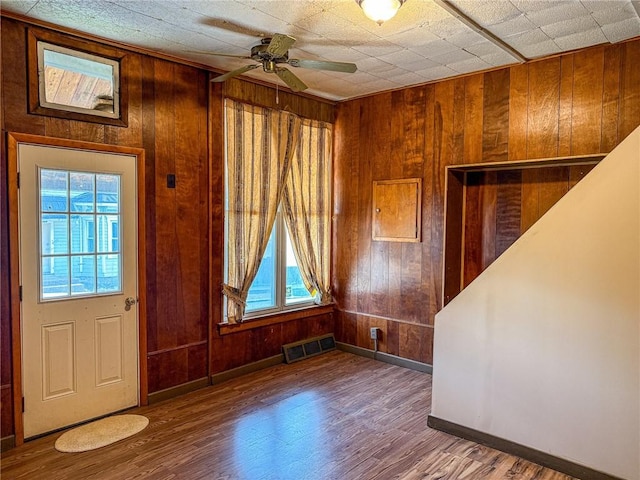 foyer with visible vents, a ceiling fan, wood finished floors, and wood walls