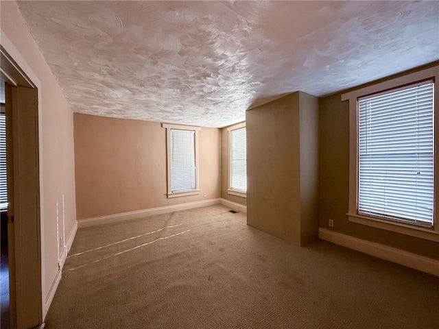 carpeted spare room with visible vents, baseboards, and a textured ceiling