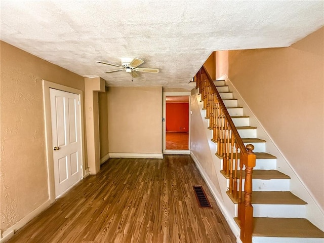 staircase featuring visible vents, ceiling fan, wood finished floors, and a textured ceiling