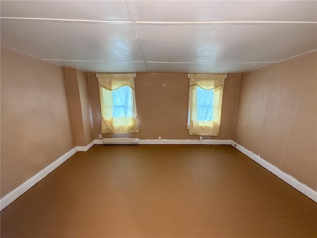 empty room with dark colored carpet, a baseboard radiator, and baseboards