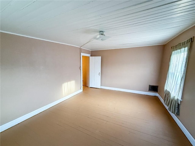 unfurnished room featuring wood-type flooring, baseboards, and visible vents