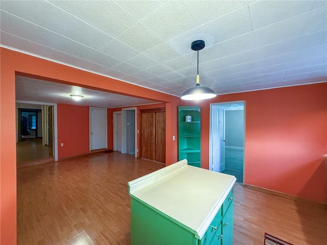 kitchen with hanging light fixtures, a center island, baseboards, light countertops, and light wood-style flooring