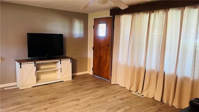 unfurnished living room featuring light wood finished floors, visible vents, baseboards, and ceiling fan