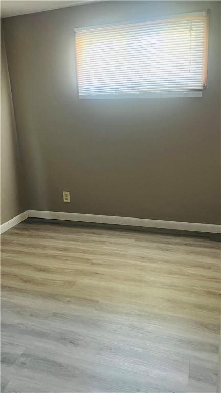 empty room with baseboards, wood finished floors, and a healthy amount of sunlight