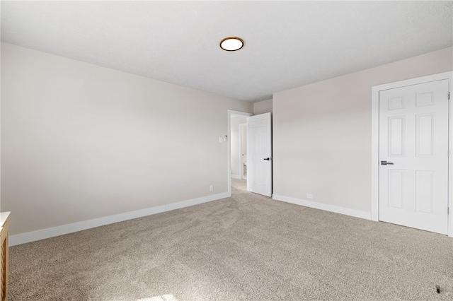 unfurnished room with light carpet and baseboards