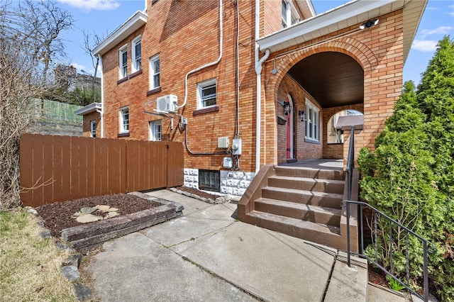 doorway to property with a porch, fence, and brick siding
