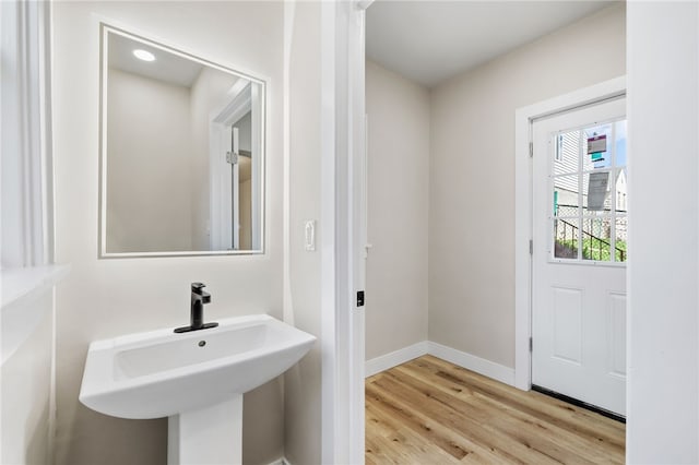 bathroom with a sink, baseboards, and wood finished floors