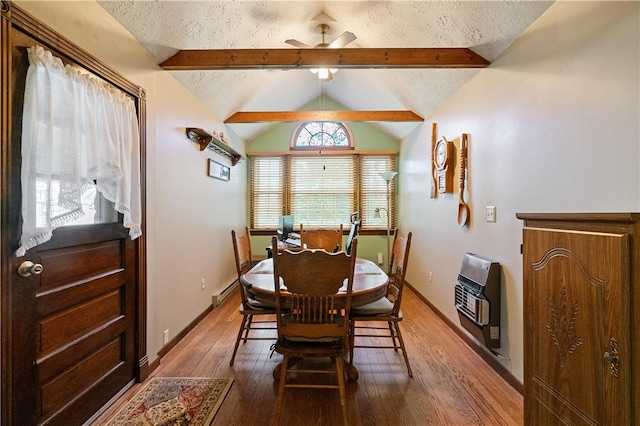 dining space with ceiling fan, wood finished floors, a baseboard heating unit, vaulted ceiling with beams, and heating unit