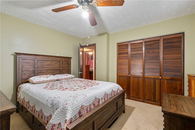 bedroom with a closet, light colored carpet, a textured ceiling, and ceiling fan
