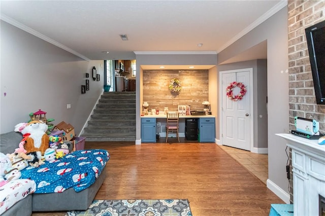 living area with light wood finished floors, a fireplace, stairs, and crown molding