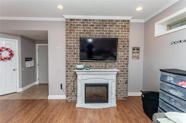 living room with baseboards, wood finished floors, a fireplace, and crown molding