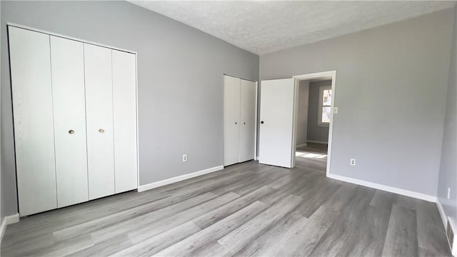 1406 Superior Ave, Brighton Heights, PA 15212 - unfurnished bedroom with light wood-style flooring, baseboards, two closets, and a textured ceiling