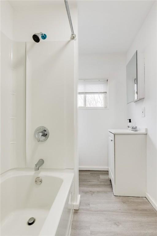 full bathroom featuring baseboards, wood finished floors, vanity, and bathing tub / shower combination