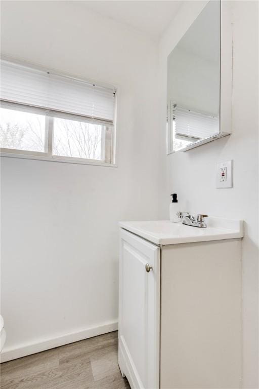 bathroom featuring toilet, vanity, wood finished floors, and baseboards