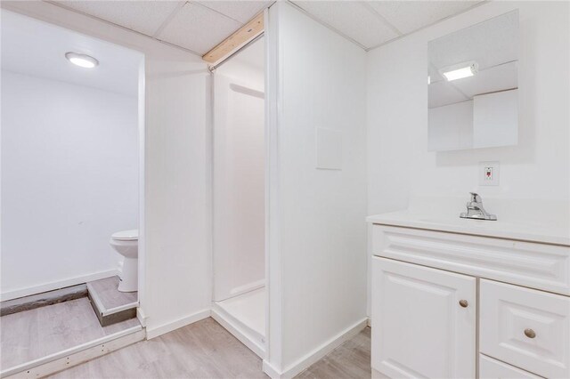 bathroom with vanity, a drop ceiling, toilet, and wood finished floors