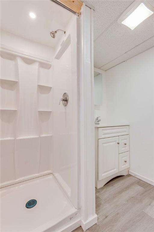 full bath featuring baseboards, a stall shower, and wood finished floors