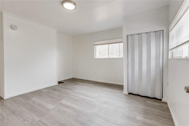 unfurnished bedroom featuring wood finished floors, baseboards, and multiple windows