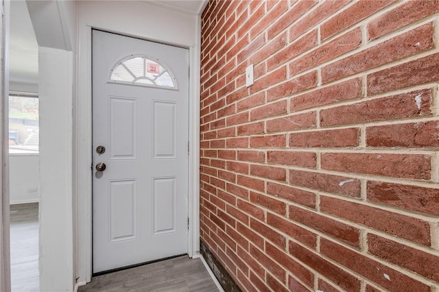 exterior space featuring brick wall and wood finished floors