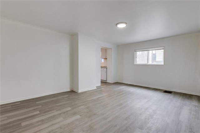 spare room featuring light wood-style flooring, baseboards, and visible vents