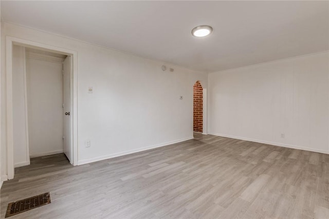 spare room featuring visible vents, baseboards, ornamental molding, and wood finished floors