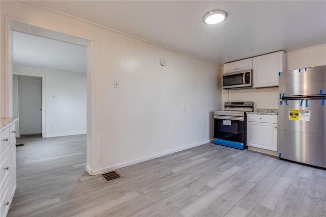 kitchen with light wood-type flooring, baseboards, white cabinetry, light stone countertops, and stainless steel appliances