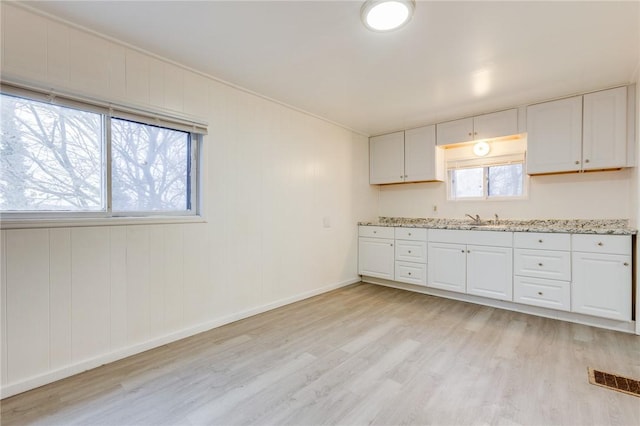 kitchen with a sink, visible vents, white cabinetry, and light wood-style floors