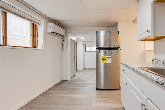 corridor with a wall mounted air conditioner, light wood-style floors, a drop ceiling, and baseboards