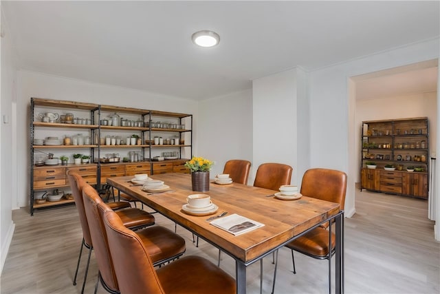 dining area with light wood-style flooring and crown molding