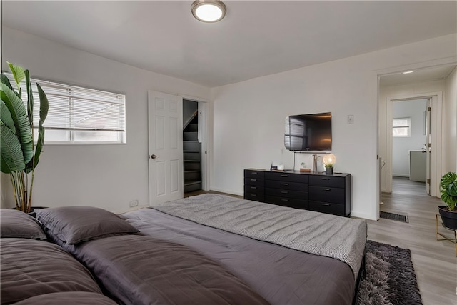 bedroom featuring light wood-style flooring, baseboards, multiple windows, and visible vents