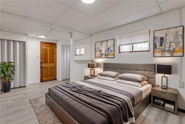 bedroom featuring a paneled ceiling, baseboards, and wood finished floors