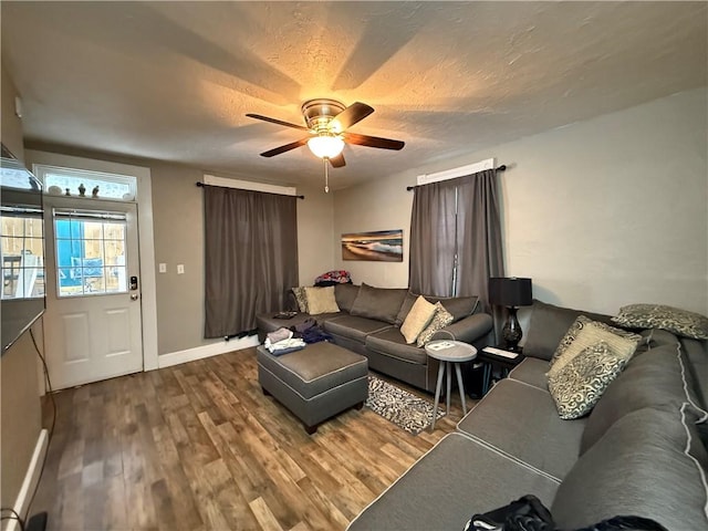 living area featuring a textured ceiling, baseboards, wood finished floors, and ceiling fan