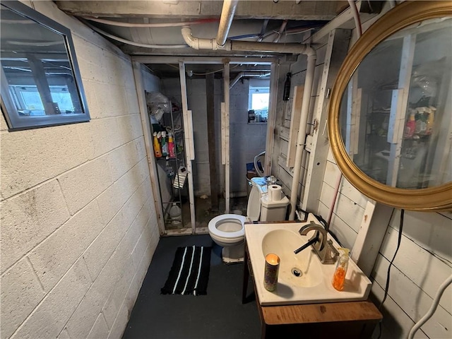bathroom with a sink, toilet, and concrete flooring