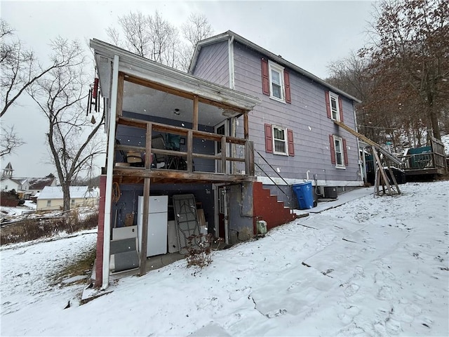 snow covered house with stairs and a wooden deck