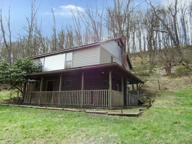 view of front of property featuring a front lawn, covered porch, and a chimney