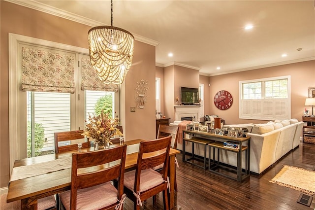 dining room featuring a fireplace, ornamental molding, recessed lighting, a chandelier, and dark wood-style flooring